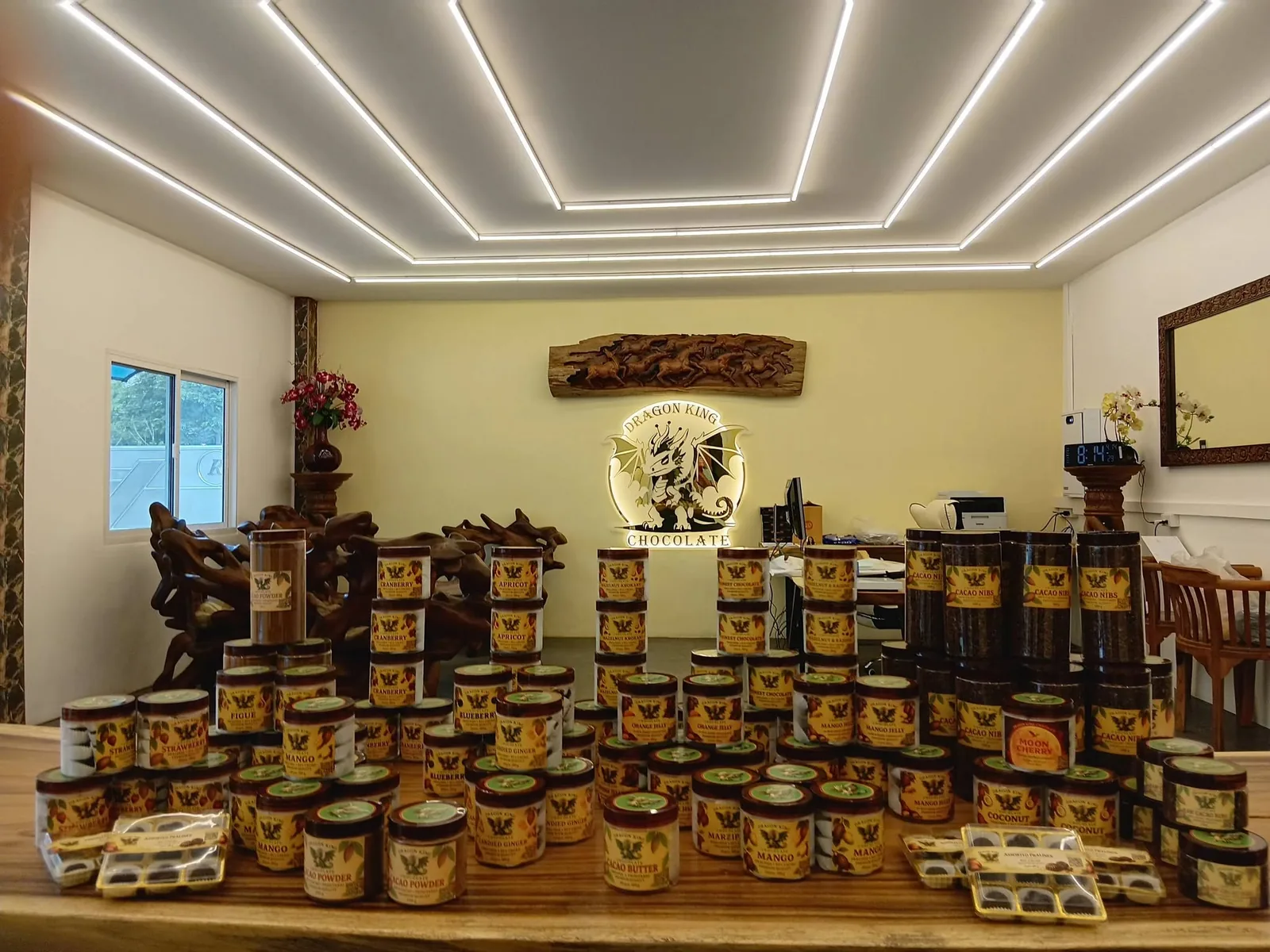 Rows of Dragon King Chocolate praline jars displayed on a table under a lit ceiling