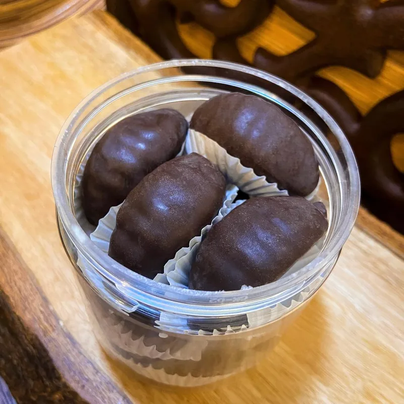Dark-chocolate-coated orange jelly pieces on a wooden board