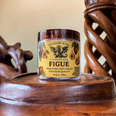 A jar of Dragon King Chocolate Figue pralines with a gold label on a carved wooden stand