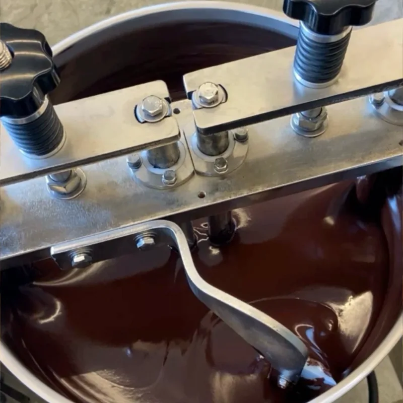 Liquid dark chocolate flowing inside a stainless steel tempering machine